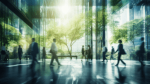 Modern office setting in a glass plaza with trees and employees walking.