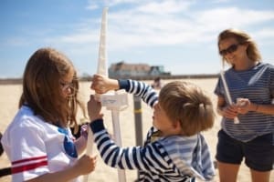 Children and mother build model offshore wind pylon on the beach at Wind4Kids event