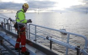 An offshore wind client rep in high-vis safety clothing on the deck of a vessel at sea.