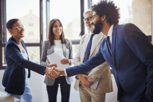 A group of four business professionals meeting. Two of them shaking hands