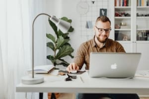 A man reading renewables and green energy newsletters on his laptop at his desk.